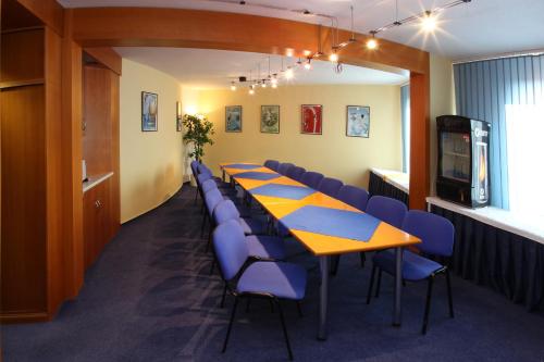 a conference room with a long table and blue chairs at Hotel Tennis Club in Prostějov