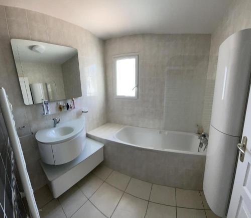 a white bathroom with a tub and a sink at La Villa de l'Olivier piscine privée et parking in Carcassonne