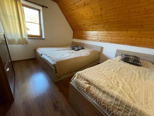 Chata u Mikiho Krahule في Krahule: سريرين في غرفة ذات سقف خشبي