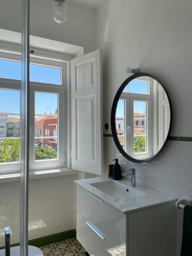 a bathroom with a mirror and a sink and windows at Casa do Mercado in Alcácer do Sal