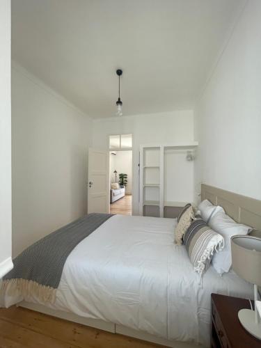 a white bedroom with a large white bed with pillows at Casa do Mercado in Alcácer do Sal