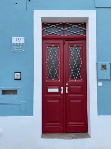 a red door on a blue and white building at Casa do Mercado in Alcácer do Sal