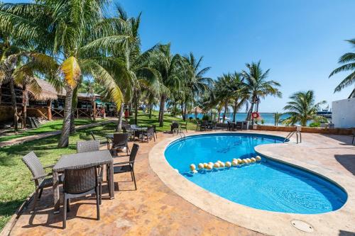 Hotel Dos Playas Faranda Cancún في كانكون: مسبح المنتجع مع الكراسي والطاولات والنخيل
