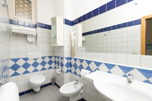 a blue and white bathroom with a toilet and a sink at Hotel Caesar in Cesenatico