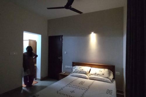 a woman standing next to a bed in a bedroom at Eka Homes 3BHDK Villa in Trivandrum