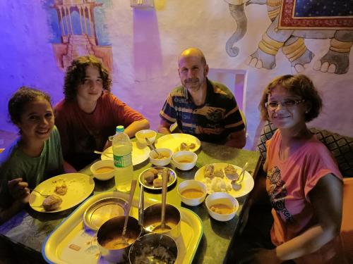 a group of people sitting around a table with food at Bhavyam HomeStay &Cafe BackPackers ko in Būndi