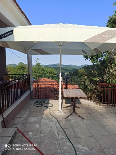 a white umbrella on a patio with a bench at House on the mountain in Kryonérion