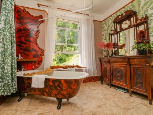 ein großes Bad mit einer großen Badewanne und einem Fenster in der Unterkunft Serenity Estate in Berrynarbor