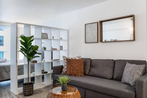 a living room with a gray couch and a mirror at Amazing Studio Apt @BRICKELL With pool & Parking in Miami
