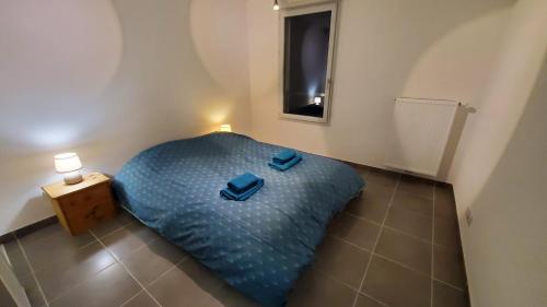 a bedroom with a blue bed with two blue slippers on it at Chez' toi Gex, proche de Genève & stations de Ski in Gex