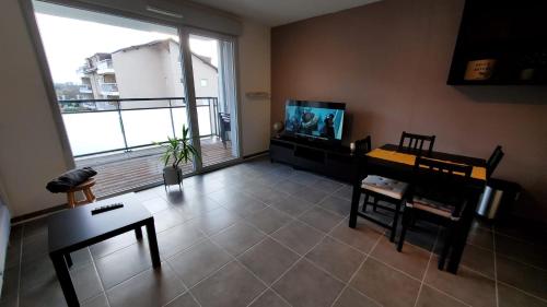 a living room with a large window and a table and chairs at Chez' toi Gex, proche de Genève & stations de Ski in Gex