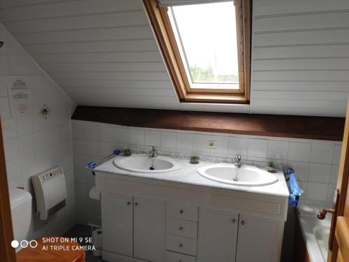 La salle de bains est pourvue de 2 lavabos et d'une fenêtre. dans l'établissement Gîte Le Grenier Cottage anglais Morbihan, à Réminiac