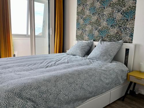 a bedroom with a bed with a blue and white comforter at Appt centre de Courseulles - 100m de la plage in Courseulles-sur-Mer