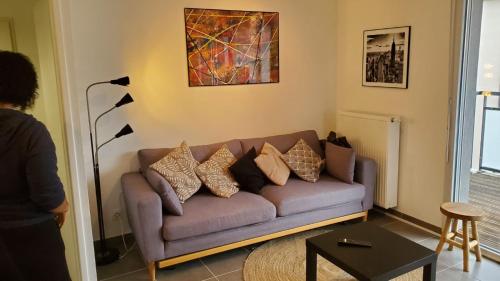 a living room with a purple couch with pillows at Chez' toi Gex, proche de Genève & stations de Ski in Gex