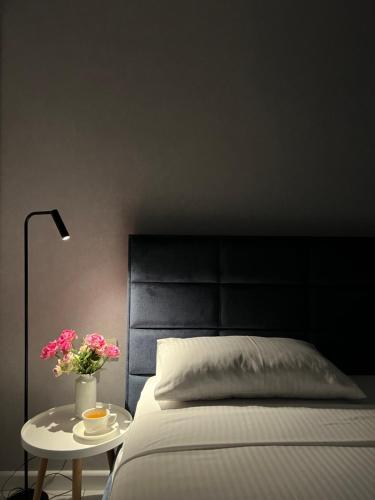 a bed with a black headboard and a table with flowers at The SPOT apartments - Orbi Beach Tower in Batumi