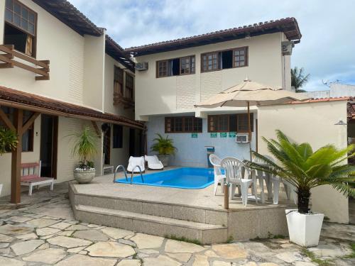 a villa with a swimming pool in front of a house at Pousada Rancho Verde in Porto Seguro