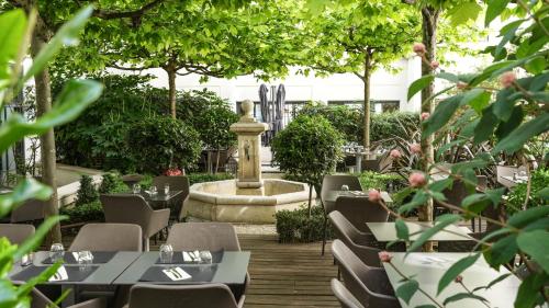 een restaurant met tafels en stoelen en een fontein bij Mercure Paris Gare Montparnasse TGV in Parijs
