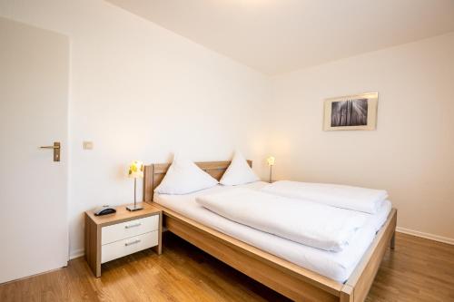 1 dormitorio con 1 cama con sábanas blancas y mesa en Gemünder Ferienpark Salzberg, en Schleiden