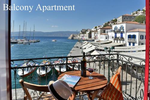 a table on a balcony with a view of the water at Hydra Port Apartments in Hydra