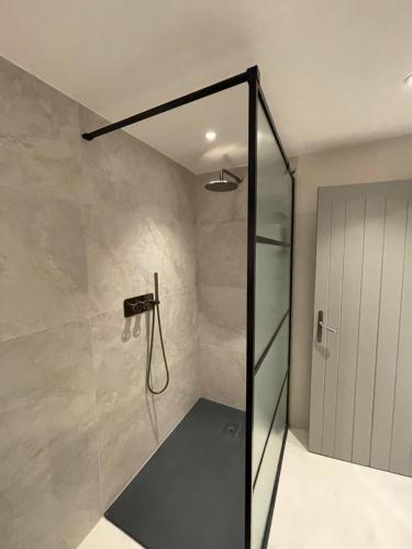 a shower with a glass door in a bathroom at 17th Century Barn near Le Manoir aux Quat’Saisons in Great Milton