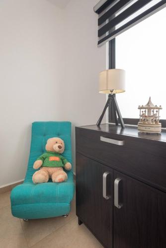 a teddy bear sitting in a blue chair next to a dresser at New Ampartment For Rent in Jarretadera