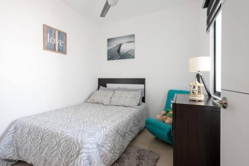 a bedroom with a bed and a blue chair at New Ampartment For Rent in Jarretadera