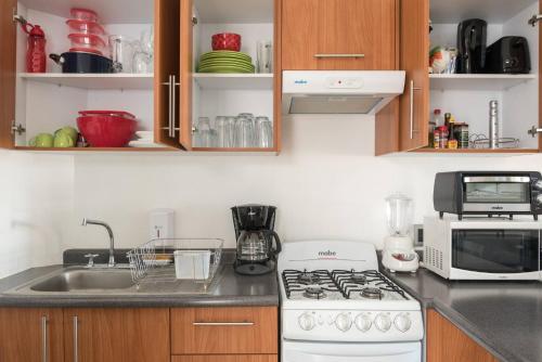 a kitchen with a white stove top oven next to a sink at New Ampartment For Rent in Jarretadera
