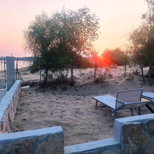 a bench and a chair on the beach at sunset at New Rooms on The Beach in Pozzallo