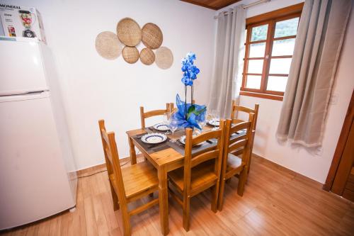 a kitchen with a wooden table with chairs and a refrigerator at Praia do Estaleiro-BC, 2 vagas, Ar, Churras e Pet Friendly in Balneário Camboriú