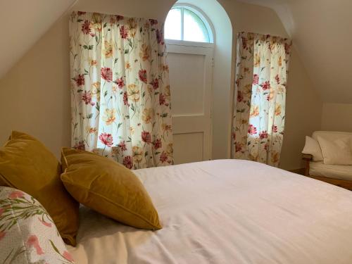 Schlafzimmer mit einem Bett und einem Fenster mit Vorhängen in der Unterkunft Hethpool Hideaway Northumberland National Park for 2 in Wooler