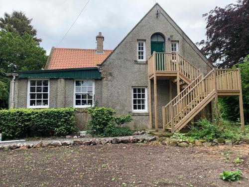una casa con una terraza de madera frente a ella en Hethpool Hideaway Northumberland National Park for 2 en Wooler