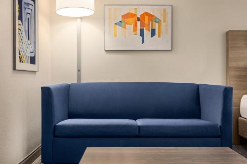 a blue couch in a living room with a painting at Holiday Inn Express & Suites Greenville-Downtown by IHG in Greenville