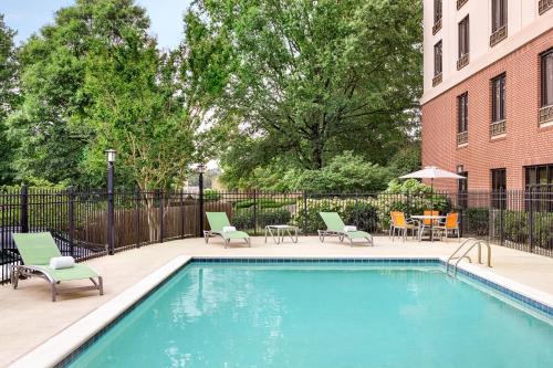 a swimming pool with chairs and tables and a building at Holiday Inn Express & Suites Greenville-Downtown by IHG in Greenville