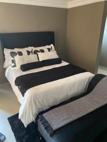 a large bed with black and white sheets and pillows at Charli’s Lodge in Mpheleng