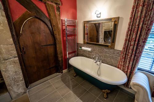 a bathroom with a bath tub and a mirror at Caravelli in Loughborough