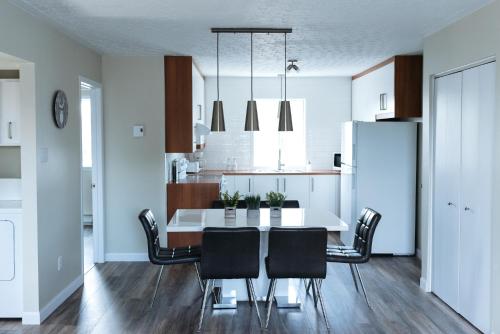 a kitchen and dining room with a white table and chairs at Le Contemporain in Rouyn