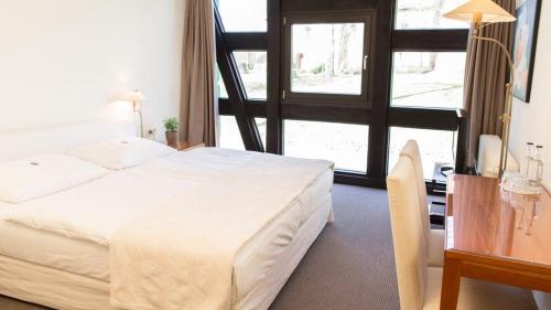 a bedroom with a bed and a table and a window at Meyers Hotel Hittfeld in Seevetal