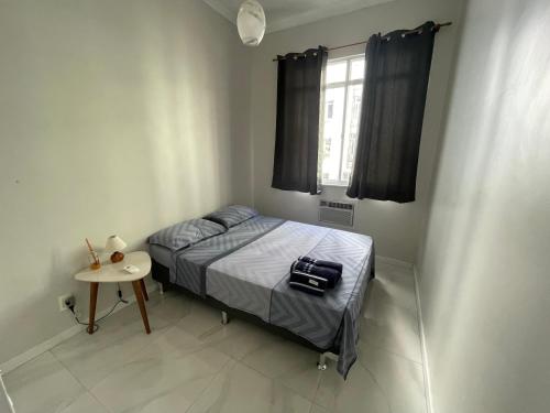 um pequeno quarto com uma cama e uma mesa em Lindo apartamento em Copacabana no Rio de Janeiro