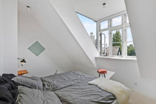 a bed in a white room with a window at Sunny 1st floor apartment in Tisvildeleje