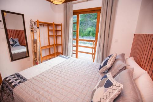 um quarto com uma cama e uma grande janela em Beleza e Conforto em Balneário Camboriú no Balneário Camboriú