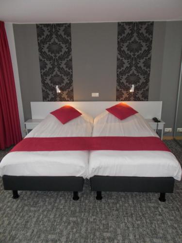 a bedroom with a bed with red and white sheets at Hotel Limburgia in Kanne