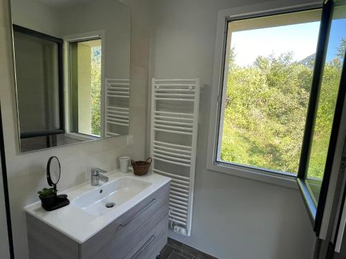 ein weißes Badezimmer mit Waschbecken und Fenster in der Unterkunft Clos du chapitre T2 - 2pers in Brides-les-Bains