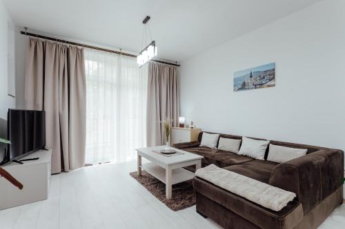 a living room with a brown couch and a table at Apartmán vo vile Kammergraf in Banská Štiavnica