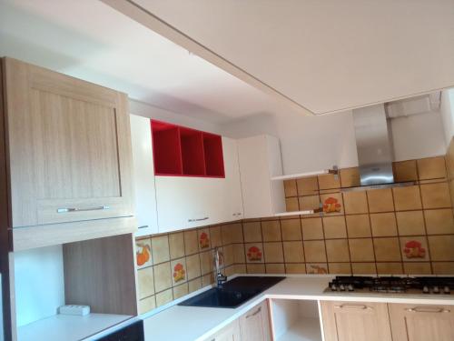 una cocina con armarios rojos y blancos y fregadero en MAISON BLANC, en Aymavilles