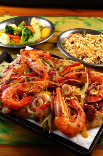 a plate of food with shrimp and rice on a table at Delphin Beach Hotel in Guarujá