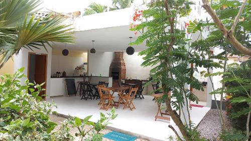 un patio al aire libre con mesa, sillas y árboles en Residence Vila Europa en Porto Seguro