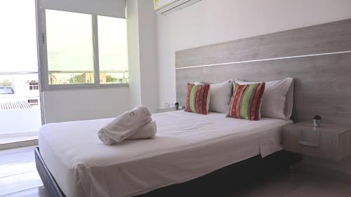 Una cama blanca con una toalla encima. en D Río Apartamentos, en Ríohacha