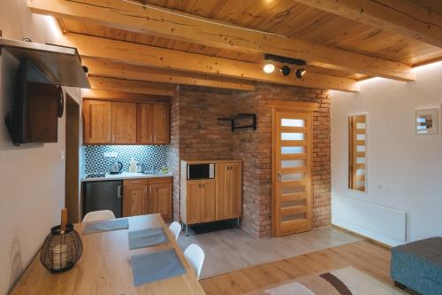 a kitchen with wooden cabinets and a table in a room at Hívlak vendégházak in Demjén