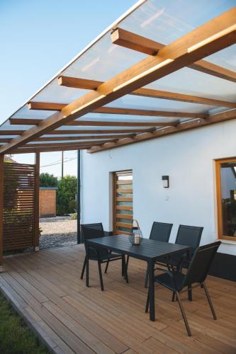 a patio with a black table and chairs on a wooden deck at Hívlak vendégházak in Demjén