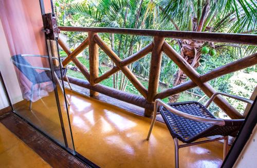a balcony with a chair and a palm tree at Pousada Altamira in Ilhabela